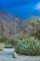 CALIFORNIA, USA - NOVEMBER 27, 2019 the flag of the USA and California on the background of the mountains. Agave in the foreground photo