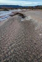 Cracked red clay and white salt on the surface in a dried riverbed in the desert of New Mexico, USA photo