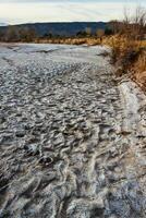 Cracked red clay and white salt on the surface in a dried riverbed in the desert of New Mexico, USA photo