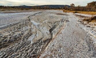 Cracked red clay and white salt on the surface in a dried riverbed in the desert of New Mexico, USA photo