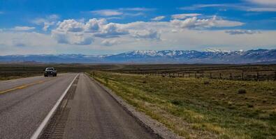 The landscape is in the wild. A road going into the distance, white clouds on the horizon. photo