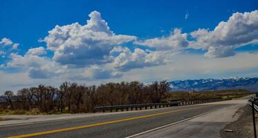 The landscape is in the wild. A road going into the distance, white clouds on the horizon. photo