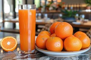 Glass of Orange Juice and Oranges in a Bowl on a Table photo