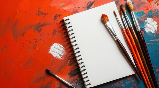 A captivating creative composition features a blank sketchbook and various painting brushes against a vibrant background of colorful splashes, enhancing the artistic atmosphere significantly photo