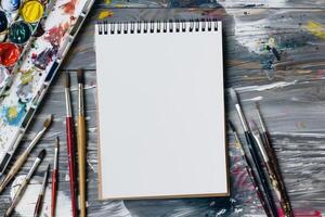 A sketchbook rests beside an array of vibrant paintbrushes and a visually striking palette, creating an inspiring environment that is perfect for developing artistic ideas and crafting unique designs photo