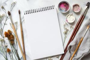 In this calm workspace, a blank sketchbook, vibrant paints, highquality brushes, and delicate dried flowers await your ideas, setting the stage for your creativity and inspiration to flourish photo