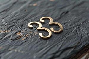 A stylish and elegant golden numeral 33 is artistically placed on a textured background, ideal for various media uses photo