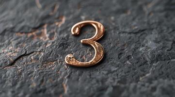A closeup view capturing a decorative copper number three beautifully placed upon a textured stone surface photo