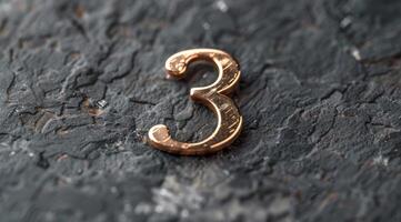 A distinctive metallic number three set on a textured dark surface, perfect for various creative projects photo