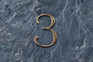 An exceptionally stylish representation of the number 3 artfully designed on a beautifully textured dark slate surface photo
