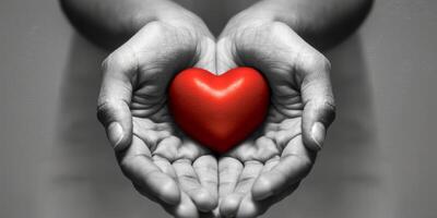 A striking and captivating image of multiple hands gently cradling a vibrant red heart against a monochrome background photo