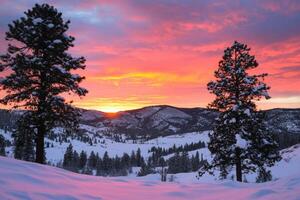 Snow-covered hills and pine trees under a vibrant sunset. photo