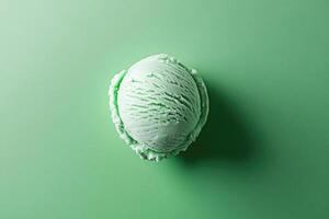 A top-down view of a mint green ice cream scoop on a mint green background. photo