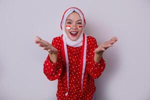 A hijab-wearing woman in a red outfit polkadot and an Indonesian flag headband poses in a celebration of Independence Day. The photo reflects patriotism and national pride.
