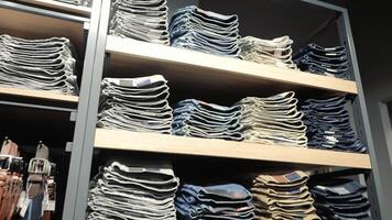 Folded Jeans on Store Shelves, Neatly folded jeans arranged on shelves in a retail store The stacks of jeans are organized by color and size video