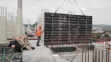 The builder works on the construction site. Installation of a large metal structure on the roof of the building video