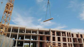 Construction Site with Crane Lifting Concrete Slab. A dynamic view of a construction site where a crane is lifting a concrete slab towards the upper levels of a building under construction. video