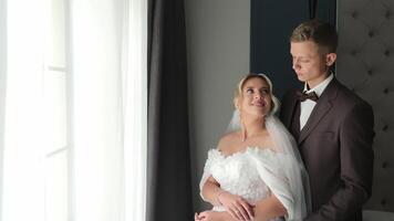 Bride and groom sharing a tender moment by the window, A beautiful image capturing the bride and groom standing together by the window video