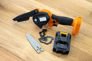 metal chain, bar and small accumulator chainsaw to trim broken branches of a tree photo