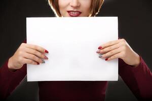 Red-haired woman holding an empty A4 card. Isolated on black background. Space for text photo