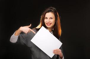 Young woman showing on empty blank board. Isolated on black background. Space for text photo