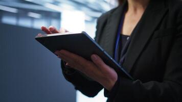 Programmer managing data center with advanced technology using digital device. Close up shot of woman walking in server room, optimizing data center tech with tablet, camera B photo