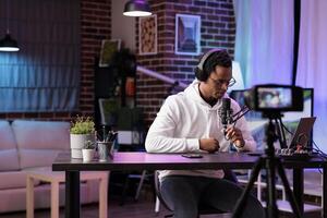 Vlogger recording internet show using modern camera checking comments left by fans. Man filming content for online vlog, reading remarks left by supporters on his channel videos photo