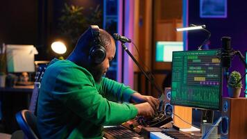 Sound engineer mixing and mastering new music on console and daw software in home studio, twisting pre amp knobs. Talented composer producing songs for the industry. Camera A. photo