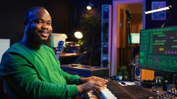 Modern producer playing piano keys to record new soundtrack, trying to produce song using midi controller electronic keyboard. Songwriter composer playing instrument notes to create tunes. Camera B. photo