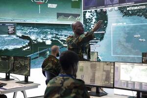 Communications engineer monitoring radar surveillance footage on a big screen in command post, gather intelligence for a new military operation program. Soldier working in defense division. photo