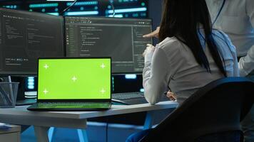 Programmer in data center managing and maintaining databases using chroma key notebook, ensuring data integrity and security. Expert updating server room systems using isolated screen laptop, camera A photo