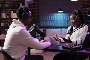 Online show host interviewing african american woman sharing financial advice during business focused podcast. Talking show interviewer using professional mic and decor to broadcast interview live photo
