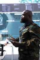 Team of military specialists monitors satellite data and real time information, coordinates strategic missions. Working on decision making and national security in a high tech operations room. photo
