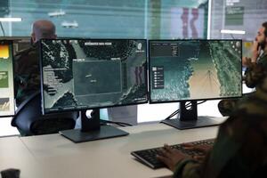 Army personnel operating on CCTV radar system for mission reconnaissance, national safety protocols in control center. IT engineer verifying ships anchoring in the ports, satellite images. photo