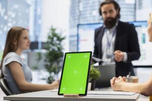 Focus on isolated screen tablet used by counselor in blurry background to show people financial plan. Close up shot of chroma key notebook used by advisor to teach clients how to increase income photo