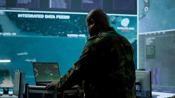 Army espionage specialist in a control center collecting satellite cctv data real time surveillance, strategic military operations. Working to ensure national security and protocols. Camera A. photo