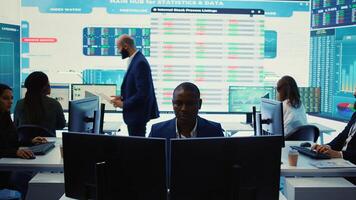 Chief executive officer reviewing project details about achieving business goals, establishing resource allocation. Administrator works in a firm monitoring room with big screen. Camera B. photo