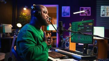 Artist producer singing a new song to record on microphone, preparing to edit music in post production. Musician expert applying mixing and mastering techniques on his audio recorded files. Camera B. photo