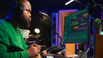 Music technician with headset mixing and mastering his audio recordings, operating on console in home studio. Musician producer creating new tunes with sound effects in post production. Camera B. photo