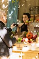 Small farm business owner stands behind counter, selling fresh organic fruits and vegetables. Female vendor and senior customer talking about healthy locally grown bio produce. photo