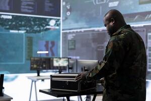 Military specialist in a command post uses advanced technology and high tech gear to gather intelligence from satellite cctv footage and computer surveillance systems to communicate information. photo