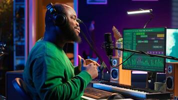 Artist composer recording a new track on his home studio microphone, editing his song with professional gear. Adjusting volume levels and adding sound effects, mix and master. Camera A. photo