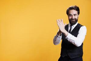 Positive employee clapping hands on camera, feeling happy after finding out about success. Young man with butler occupation applauding and giving confidence boost to person, cheering. photo