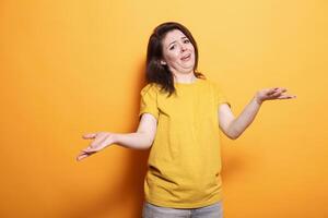 Portrait of clueless woman raising her hands and shoulders, unsure of the question. Caucasian lady with doubts is standing over isolated background with an uncertain and confused expression. photo