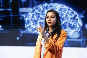 IT technician speaking at tech event, explaining impact of AI technology on world. Woman presenting risks and threats associated with AI during conference, pointing to screen photo