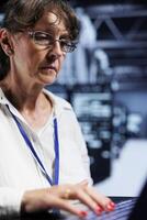 Elderly expert preparing server hub recovery plan monitoring data center energy consumption across parts, making sure sensors are functioning optimally, doing annual disk checks photo