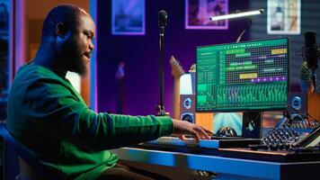 Artist playing piano electronic keyboard and recording new sounds, producing new midi controller notes in his home studio. Audio producer working with digital audio workstation software. Camera A. photo
