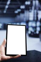 Experienced admin using mock up tablet to check operational server cabinets. Rigs in computer network security data center providing processing and memory resources for several workloads photo