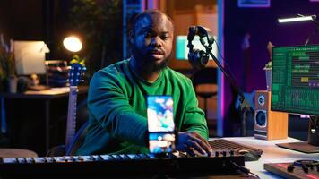 Artist songwriter hosting online master class to teach piano lessons on internet vlog, electronic keyboard notes in home studio. Young composer playing on synthesizer, recording . Camera A. photo