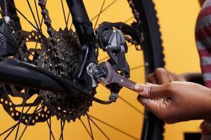 Detailed view of person grasping expert work tool for maintaining and repairing damaged bicycle. Close-up shot shows expertly and precisely adjusted parts being adjusted by african american hands. photo